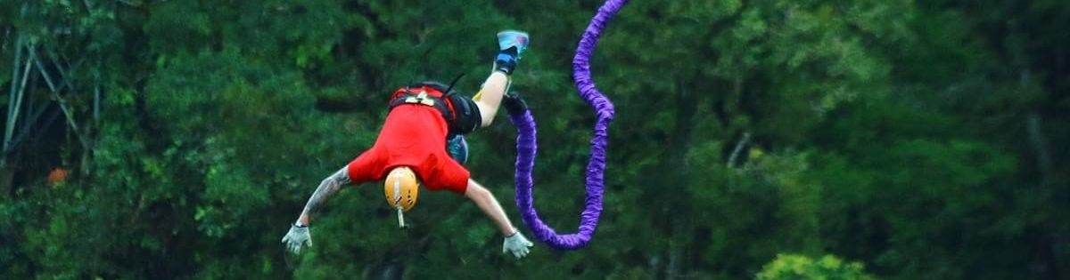 Bungee jumper mid-dive with a vibrant green forest backdrop at Monteverde Extremo Park, Costa Rica.