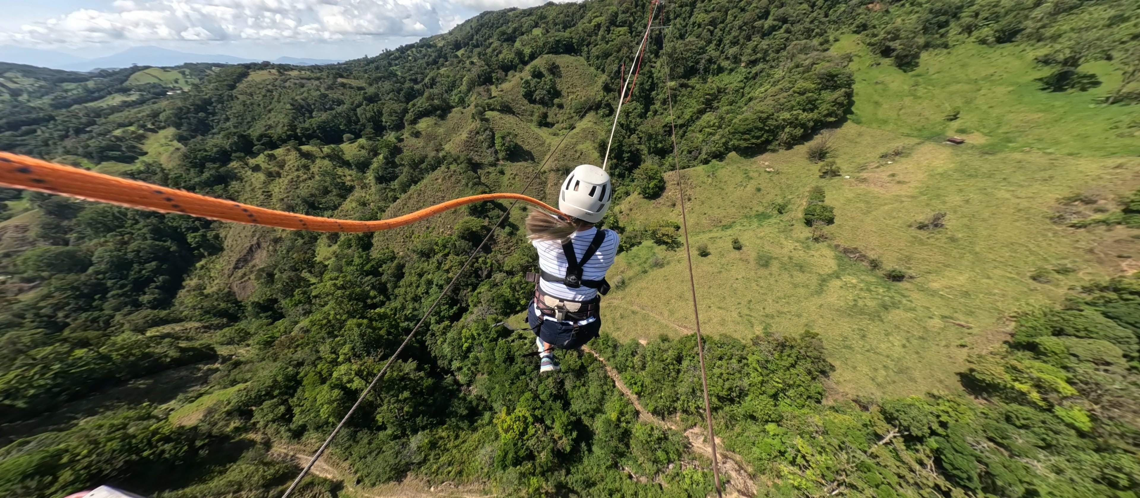 A person enjoying the Tarzan Swing at Monteverde Extremo Park, swinging over stunning green landscapes.