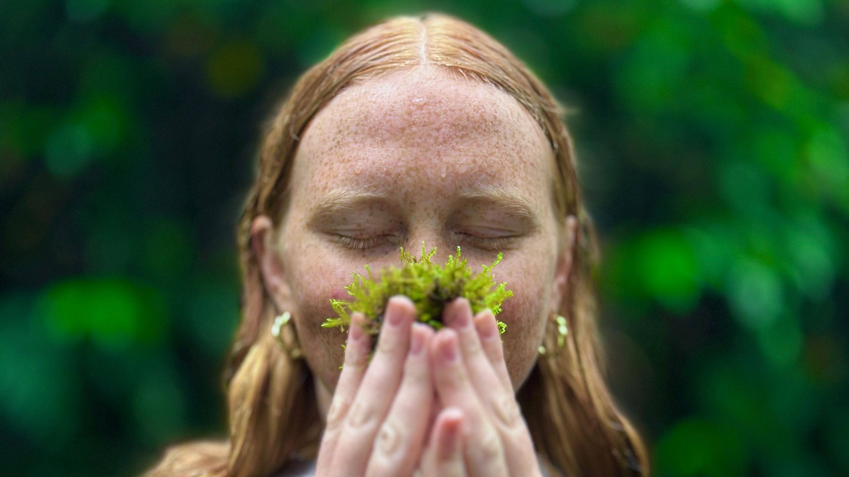 Mulher apreciando o aroma da natureza na floresta nublada de Monteverde, cercada por vegetação exuberante.