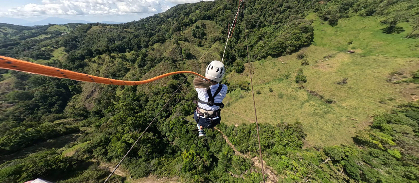 Person enjoying the Tarzan Swing at Monteverde Extremo Park, swinging over stunning green landscapes.